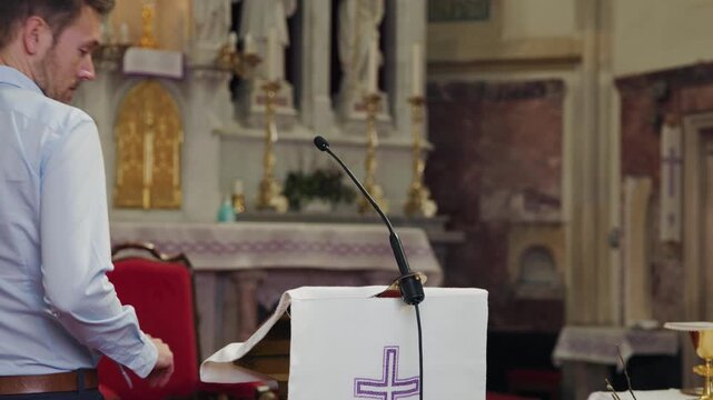 Preacher standing behind a pulpit with a microphone in a church, reading from a Bible to deliver a sermon, homily, or lead prayer.
