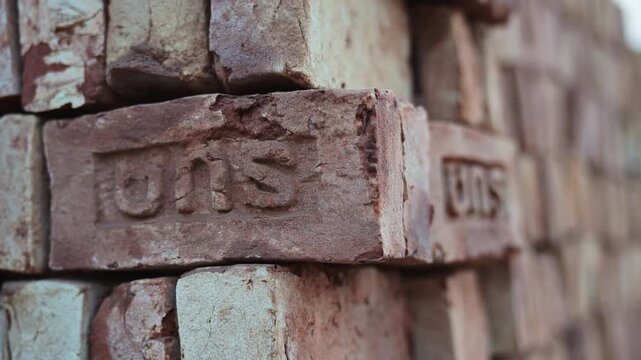 Detailed narrow-focus view of raw construction blocks stacked inside a manufacturing yard in Dhaka, Bangladesh. Highlights macro texture details, structural supply assets, and physical labor output.