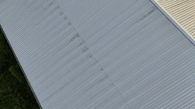 A drone view shows the symmetrical corrugated metal roof panels on a large-scale industrial warehouse building.