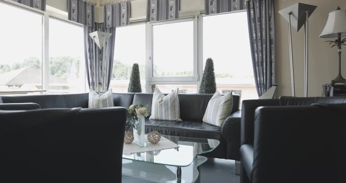 A comfortable living area with a dark leather sofa and glass coffee table inside a bright room