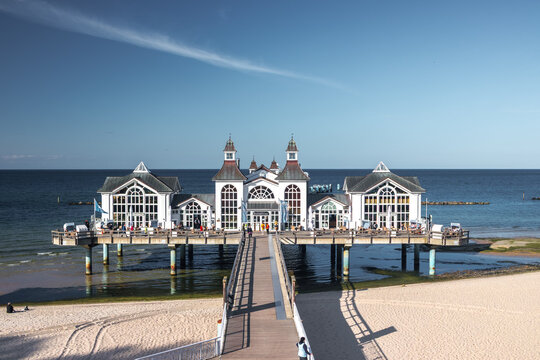 Frontal view of the iconic white Seebrucke Sellin pier building stretching out over the clear blue waters of the Baltic Sea on Ruegen island, Germany.
