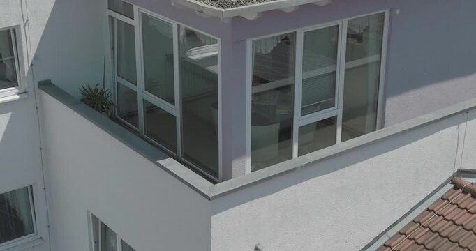 A close up view of a balcony on the corner of a modern building with large glass windows