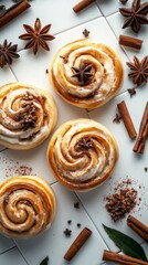 Fototapeta premium Golden cinnamon rolls with white icing and star anise rest on a tiled background, surrounded by aromatic spices.