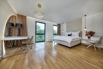 Sypialnia w nowoczesnym apartamencie z dużym  łóżkiem, fotelami, kwiatami i beżową szafą © arteffect.pl