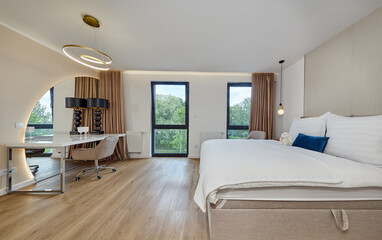Sypialnia w nowoczesnym apartamencie z dużym  łóżkiem, fotelami, kwiatami i beżową szafą © arteffect.pl