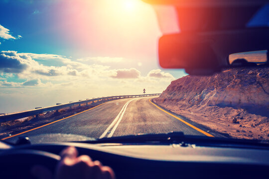 Driving a car on the mountain road in the desert. View of sandstone mountains through the windscreen. The road from Arad to the Dead Sea. Israel