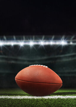 Game Day Essence. Close-up of an American football on the lush field with stadium lights looming in the background.