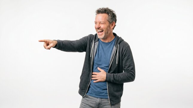 Joyful middle-aged man in a casual hoodie laughing heartily and pointing to the side on a white background.
