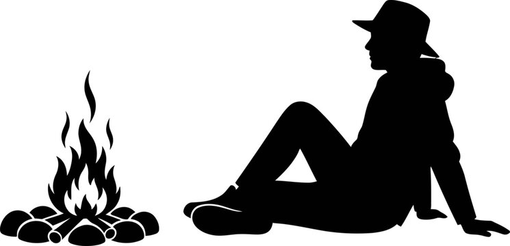 Silhouette of a person wearing a hat sitting by a campfire.