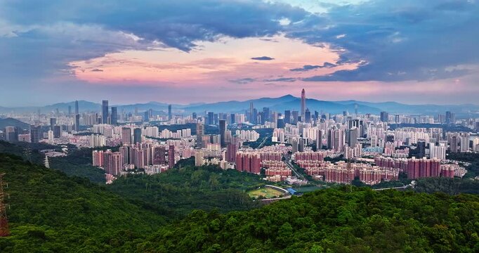 Aerial view of sprawling urban city skyline and mountains at sunset in Shenzhen, China