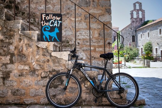 Bicycle Parked by a "Follow the Cat" Sign in Old Town Budva, Montenegro