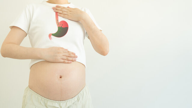 Indigestion and heartburn in pregnancy. Pregnant woman suffering from acid reflux, nausea and bloating due to hormonal changes. Health problems in pregnancy.