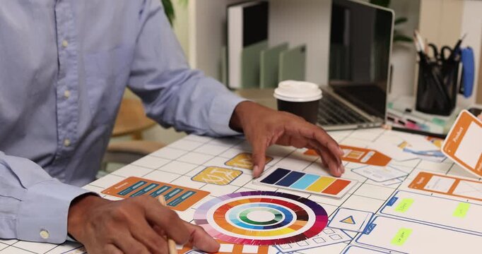 Creative team collaborating on UX and UI design using wireframes, interface components, color palettes, and planning materials to develop digital products through design thinking and teamwork.