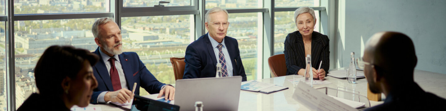 Header of senior business executives meeting with client, discussing oil industry strategy around conference table. Ideal for energy sector leadership, corporate negotiation, investment planning