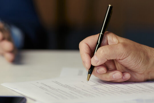 Close up of middle aged businessman signing contract during oil industry business meeting, confirming partnership and negotiation. Useful for energy sector deals, compliance, investment
