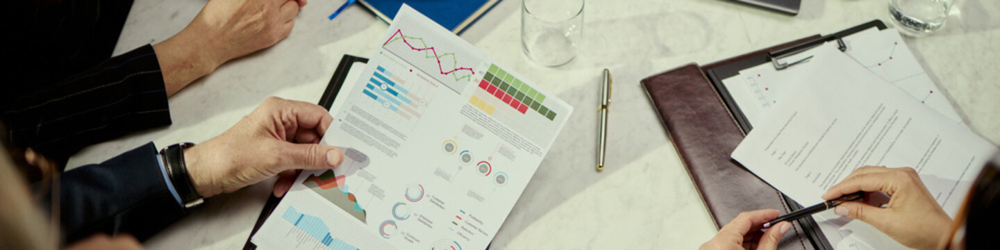 Close up header of business team reviewing charts during oil industry meeting, discussing performance metrics, planning strategy. Ideal for energy sector reports, corporate presentations