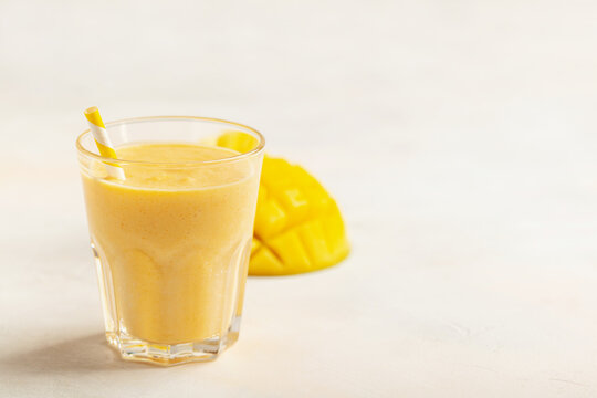 Smoothie or milkshake with a mango in a glass on the table.  Diet nutrition. Copy space