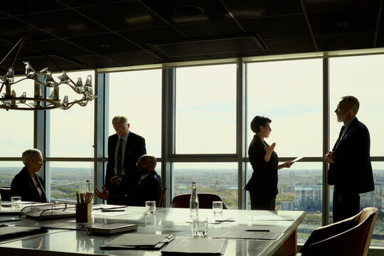 Wide shot of diverse business executives discussing strategy during oil industry meeting in high rise boardroom. Suitable for energy leadership, corporate planning, investor relations