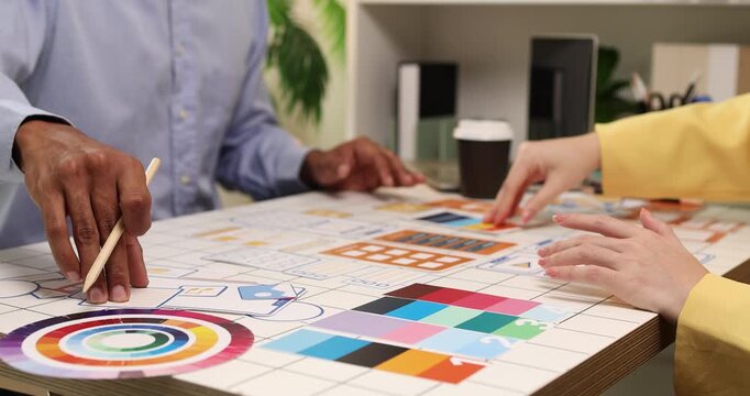 Creative team collaborating on UX and UI design using wireframes, interface components, color palettes, and planning materials to develop digital products through design thinking and teamwork.