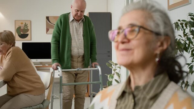 Senior woman smiling in nursing home while senior man walking with walker in background. Video promoting senior care services, retirement homes, and assisted living