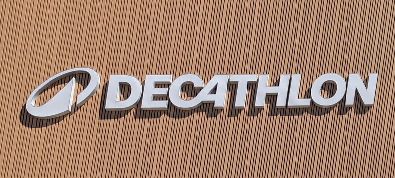 R&oacute;tulo con texto Decathlon en letras 3d de color blanco sobre listones de madera, en fachada de tienda de deportes 