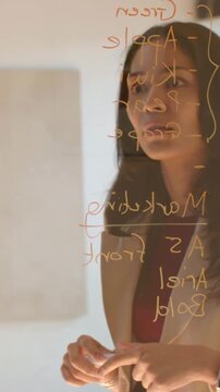 Vertical video: Entering peer pointing at glass, lead in blazer holding marker, planning Marketing
