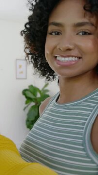 Vertical video: Raising phone, woman in mustard top filming selfie at home friend joining posing