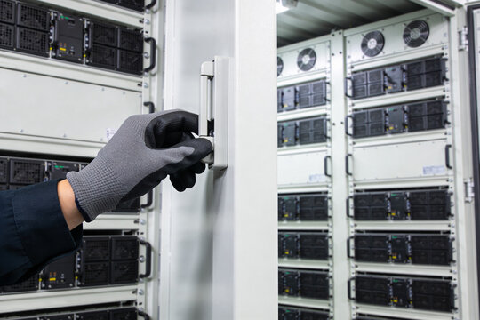 Technician wearing gloves opens a server rack door in a data center