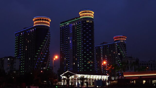Luminous modern skyscrapers of orbi city in batumi, georgia, glowing with vibrant, colorful led lights against the dark evening sky, showcasing contemporary urban architecture and design