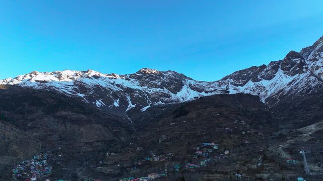 Scenic Aerial View of Sangla Valley Surrounded by Himalayan Mountains with Green Forests, Flowing River, Beautiful Village Landscape, Snow Peaks, Cloudy Sky and Breathtaking Himalayan Nature Scenery