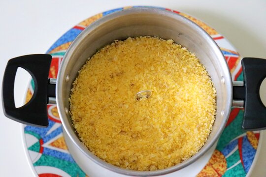 Brazilian couscous made of corn flour steaming inside a specific pan called cuscuzeiro, conceptualizing authentic Brazilian food and regional cuisine.