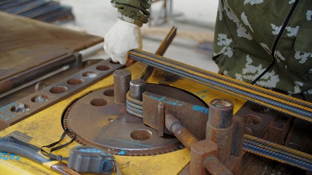 Worker operating rebar bending machine at construction site