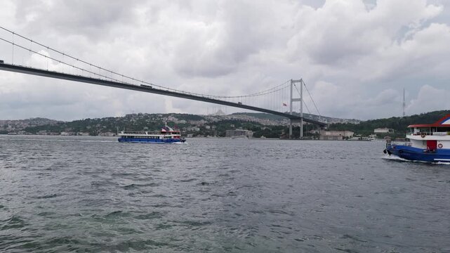 Ferry boat crossing the bosphorus strait under the famous 15 july martyrs bridge in istanbul