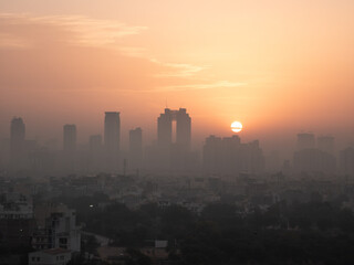 Fototapeta premium Aerial drone shot sunrise high rise skyscraper buildings at hidden in smog showing the cityscape of Gurgaon Delhi India