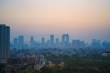 Fototapeta premium Aerial drone panning shot sunrise high rise skyscraper buildings at hidden in smog showing the cityscape of Gurgaon Delhi India