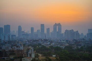 Fototapeta premium Aerial drone panning shot sunrise high rise skyscraper buildings at hidden in smog showing the cityscape of Gurgaon Delhi India