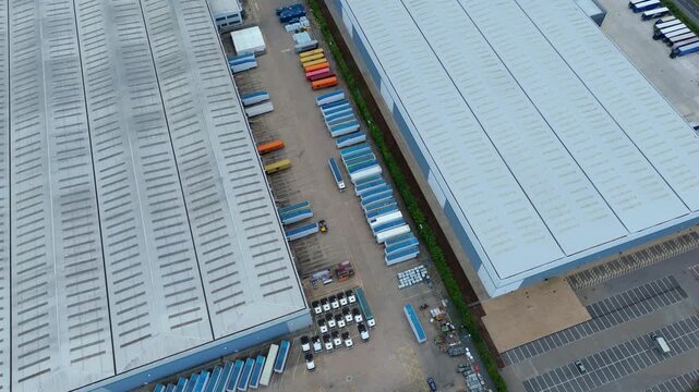 Aerial view of commercial warehouses with rows of parked trucks and trailers at a logistics distribution center in Kettering, England, United Kingdom.