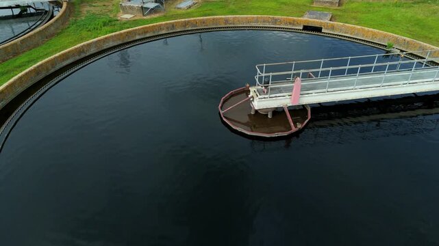 Aerial view of the circular clarifier at the wastewater sewage treatment plant with metal walkways and green grass surroundings in Hoddesdon, England, United Kingdom.