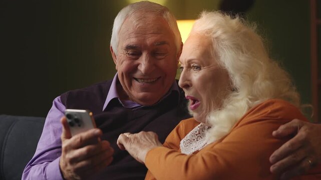 Happy couple in their 70s booking a hotel on smartphone, planning vacation
