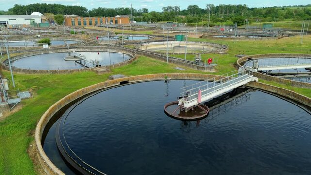 Aerial view of wastewater sewage treatment plant with circular sedimentation tanks and industrial infrastructure in Hoddesdon, England, United Kingdom.