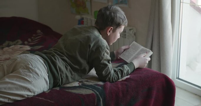 Caucasian Boy Kid Read Bible Book Lying on Bed in Bedroom. 4K 10-bit