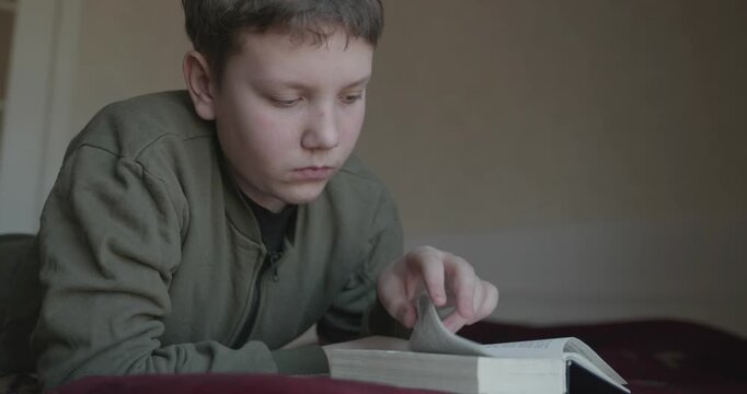 Caucasian Boy Kid Read Bible Book Lying on Bed in Bedroom. 4K 10-bit