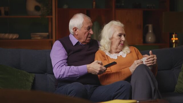 Senior couple arguing while choosing a movie to watch, wife takes the remote