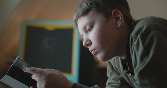 Caucasian Boy Kid Read Bible Book Lying on Bed in Bedroom. 4K 10-bit