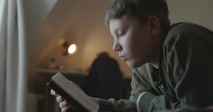 Caucasian Boy Kid Read Bible Book Lying on Bed in Bedroom. 4K 10-bit