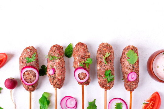 Mutton Lula Kebab on skewers in a row on white table. Caucasian cuisine meal. Top view. Copy space
