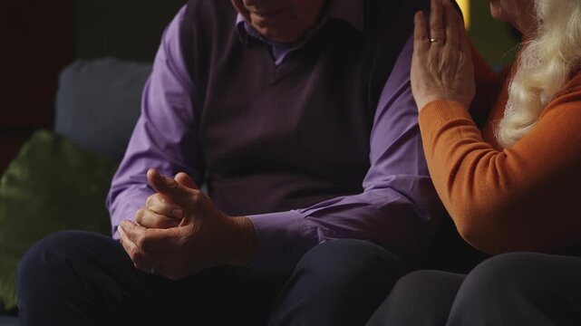 Caring elderly woman consoling and hugging her upset husband, family support