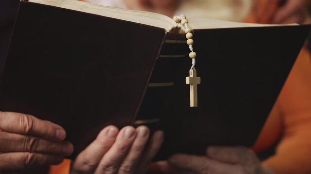 Senior couple reading the Bible with prayer beads and cross, Christian faith
