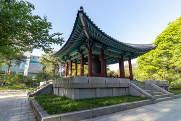 Fototapeta premium Wide angle view of traditional Korean pavilion with bronze bell shrine in spring park