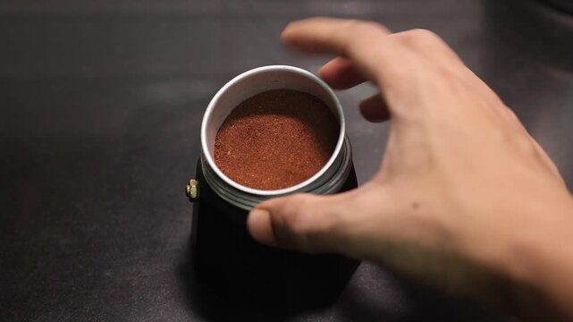 putting ground coffee over the moka pot.